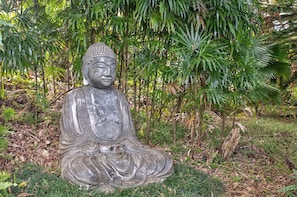 Une statue de Bouddha en pierre, dans un jardin.