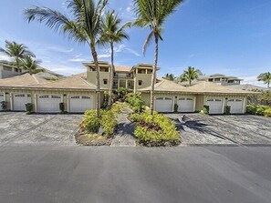 A two-story house with a garage, surrounded by palm trees and a paved driveway. - Waikoloa Beach S O-33 2 Bedroom Condo by RedAwning (Waikoloa)