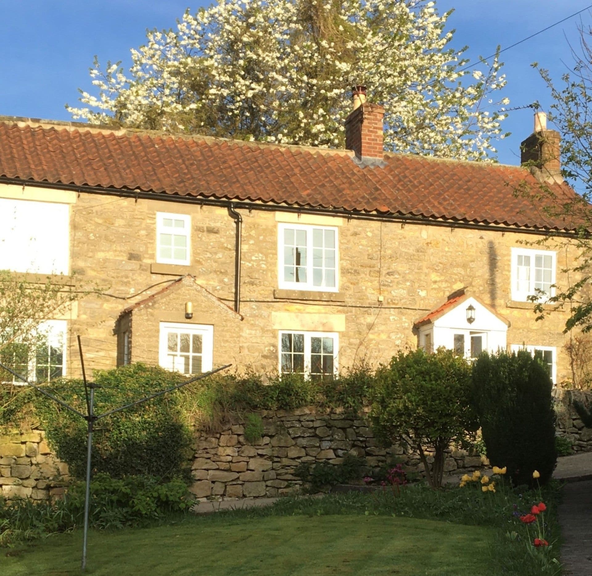 A stone building with a tiled roof, multiple windows, and a stone wall.