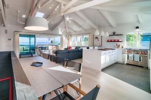 Un vaste espace de vie comprenant une grande table à manger, un canapé et une cuisine équipée d’appareils électroménagers modernes.
