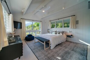 Une chambre moderne avec un grand lit, un banc, un bureau et une télévision.