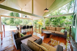 Relax in a serene outdoor space with a wooden deck, wicker sofas and chairs, and a central table.