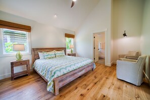 A bedroom with a wooden bed, two bedside tables, a nightstand, a chair, and a door leading to another room.