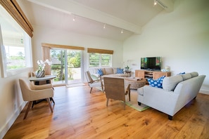 Relax in this stylish living room with a high ceiling, large windows, and a comfortable sofa.