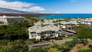 Un resort con edificios de varios pisos, una zona de piscina y vista al océano.