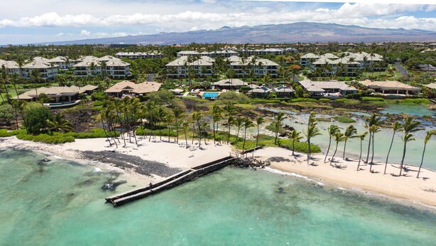 Un resort con varias construcciones, una playa y vista despejada del océano.