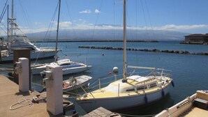 A marina with several boats docked, a clear sky, and a distant mountain range. - Maalaea Kai 316 1 Bedroom Condo by RedAwning (Wailuku)