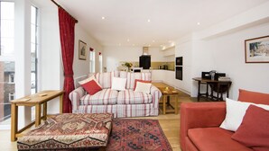 A modern living room with a striped sofa, a red couch, a wooden table, and a patterned rug. - Up-market one Bedroom Apartment Just Minutes From the River Thames. Broughton rd (London)