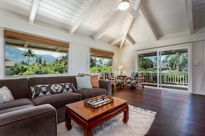 Relax in a serene space with a high ceiling, lush views, and a cozy seating area.
