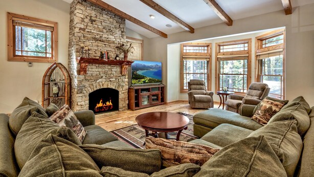 Una sala de estar acogedora con chimenea de piedra, asientos cómodos y ventanas amplias.