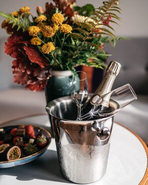 A metallic bucket with a champagne bottle and glasses, a bowl of fruit, and a vase of flowers on a table. - Rönneberga (Lidingo)