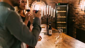 A wooden table with a bottle of wine and glasses, a candelabra with lit candles, and a brick wall in the background.