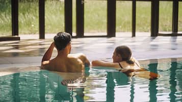 Una piscina con agua cristalina, rodeada de un suelo empedrado y amplias ventanas.