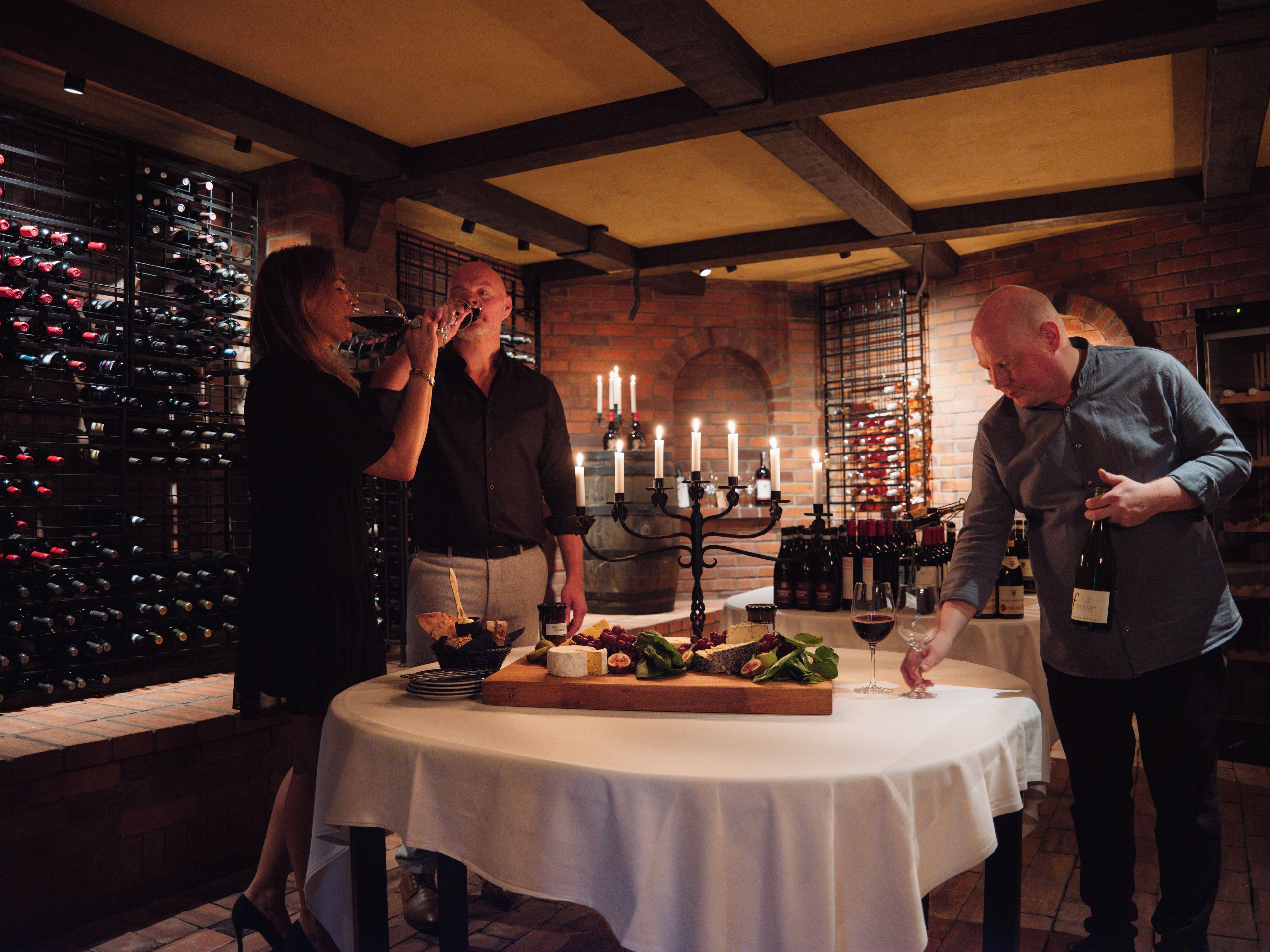 A wine tasting event with a table set for guests, surrounded by wine racks and a brick wall.