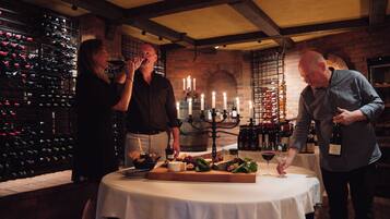 A wine tasting event with a table set for guests, surrounded by wine racks and a brick wall.