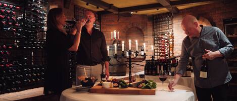 A wine tasting event with a table set for guests, surrounded by wine racks and a brick wall.