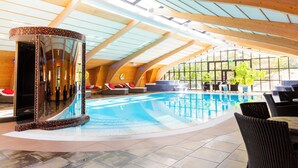An indoor swimming pool with a curved ceiling, seating areas, and a glass enclosure. - Rönneberga (Lidingo)