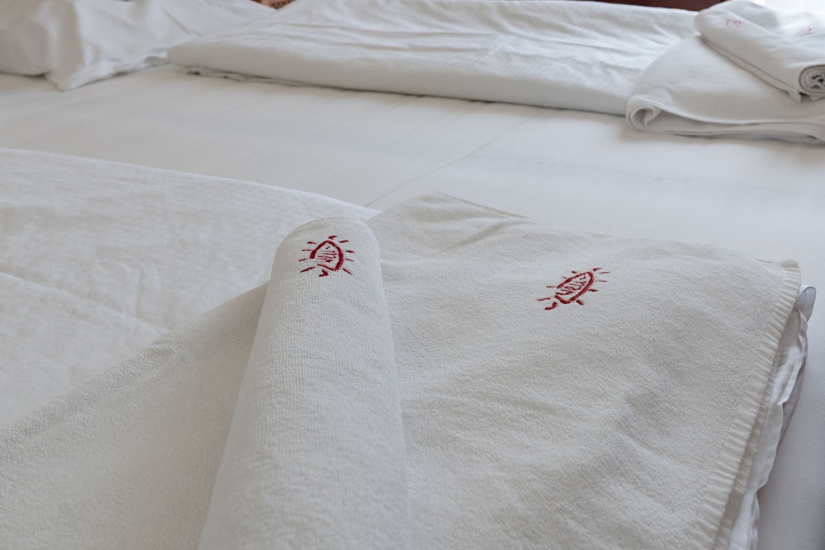 Una habitación de hotel con una cama bien hecha, una mesita de noche con lámpara y dos sillones.