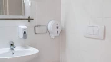 A bathroom with a white sink, a toilet, a hand dryer, and a mirror.