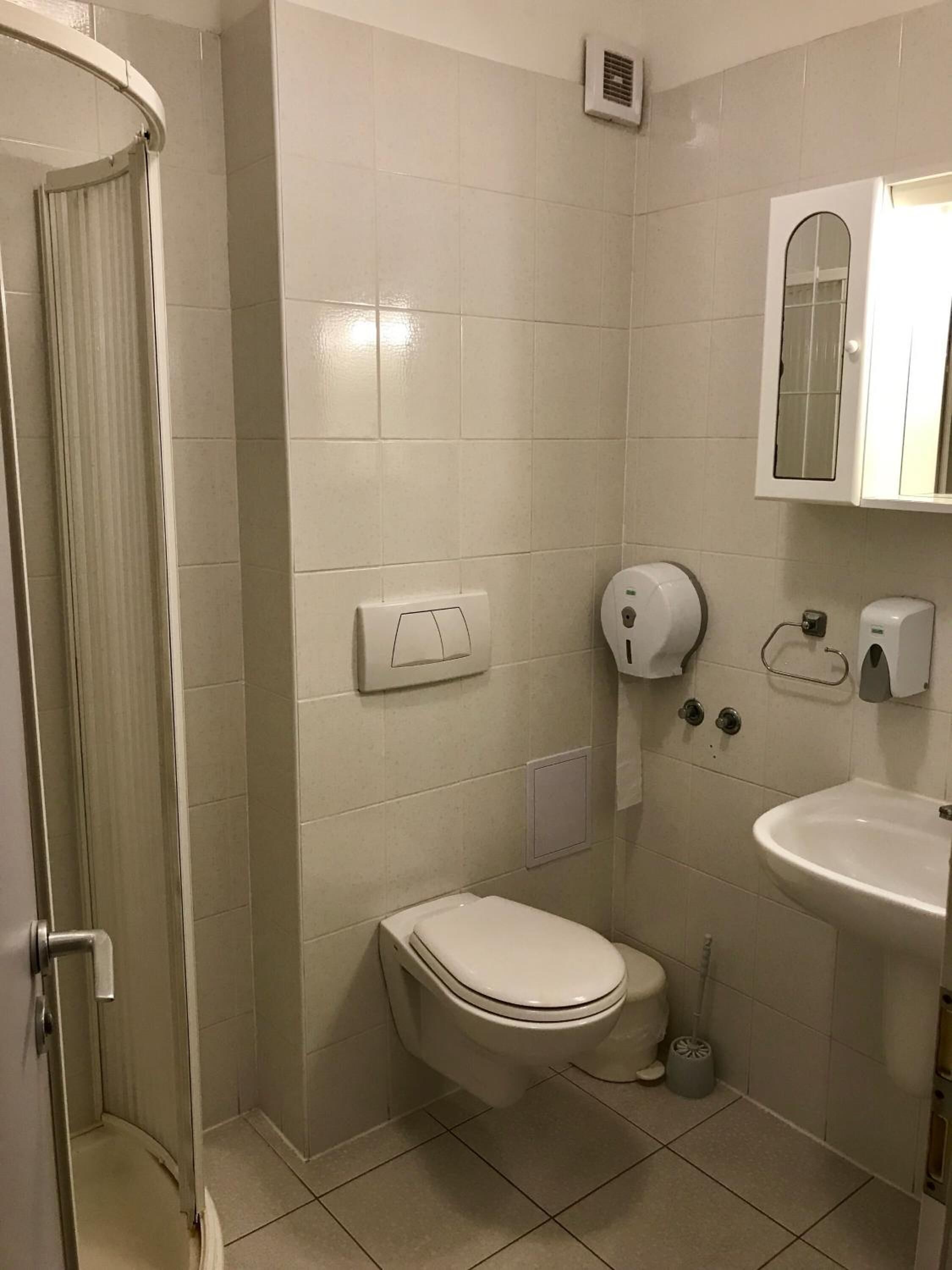 A bathroom with a toilet, sink, and shower.