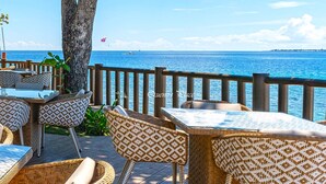 Ein Sitzbereich im Freien mit Korbmöbeln und Blick aufs Meer.