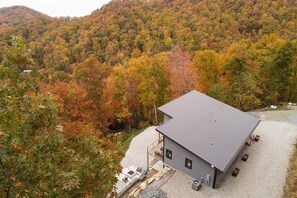 Situated in a forested area, this single-story building features a covered outdoor seating area with a fire pit.
