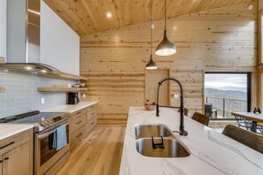 Enjoy cooking in this well-equipped kitchen with a large island, stainless steel appliances, and a window offering a view of the surrounding landscape.