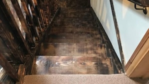 A wooden staircase with a handrail, leading to a landing with a small window. - Hillcrest Barn (Kilgetty)