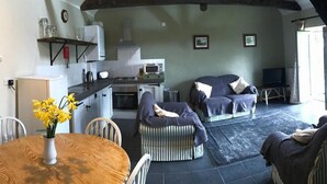 A cozy living area with a dining table, chairs, a sofa, and a TV. - Hillcrest Barn (Kilgetty)