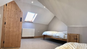 A bedroom with a sloped ceiling, a skylight, a radiator, and a bed. - Hillcrest Barn (Kilgetty)