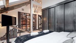 A modern hotel room with a large bed, a flat-screen TV, and a view of the interior. - Skyline Water Front Penthouse Apartment (London)