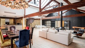 A spacious living area with a high ceiling, wooden beams, and a modern kitchen in the background. - Skyline Water Front Penthouse Apartment (London)