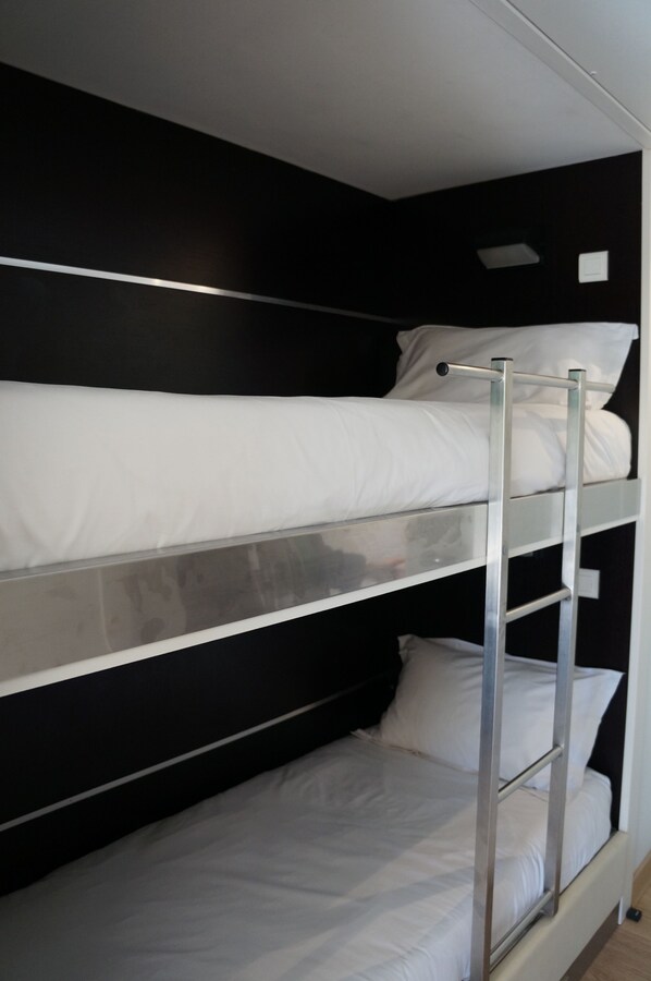 A bunk bed with metal railings and white bedding.