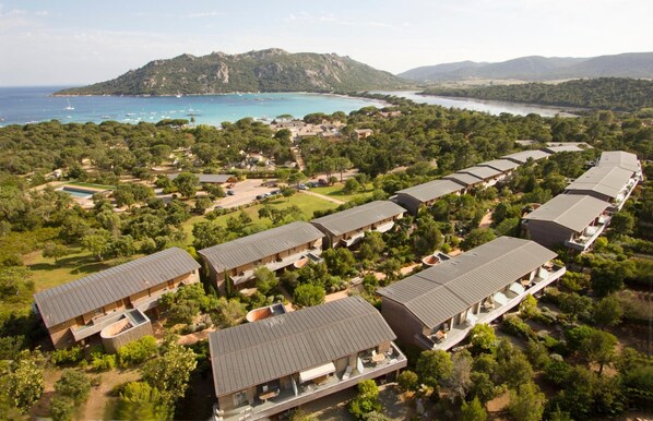 Vista aérea de un resort con varias edificaciones, una piscina y un paisaje montañoso.