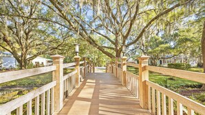 Un pont en bois, doté de garde-corps et de lanternes, entouré d’arbres et de verdure.