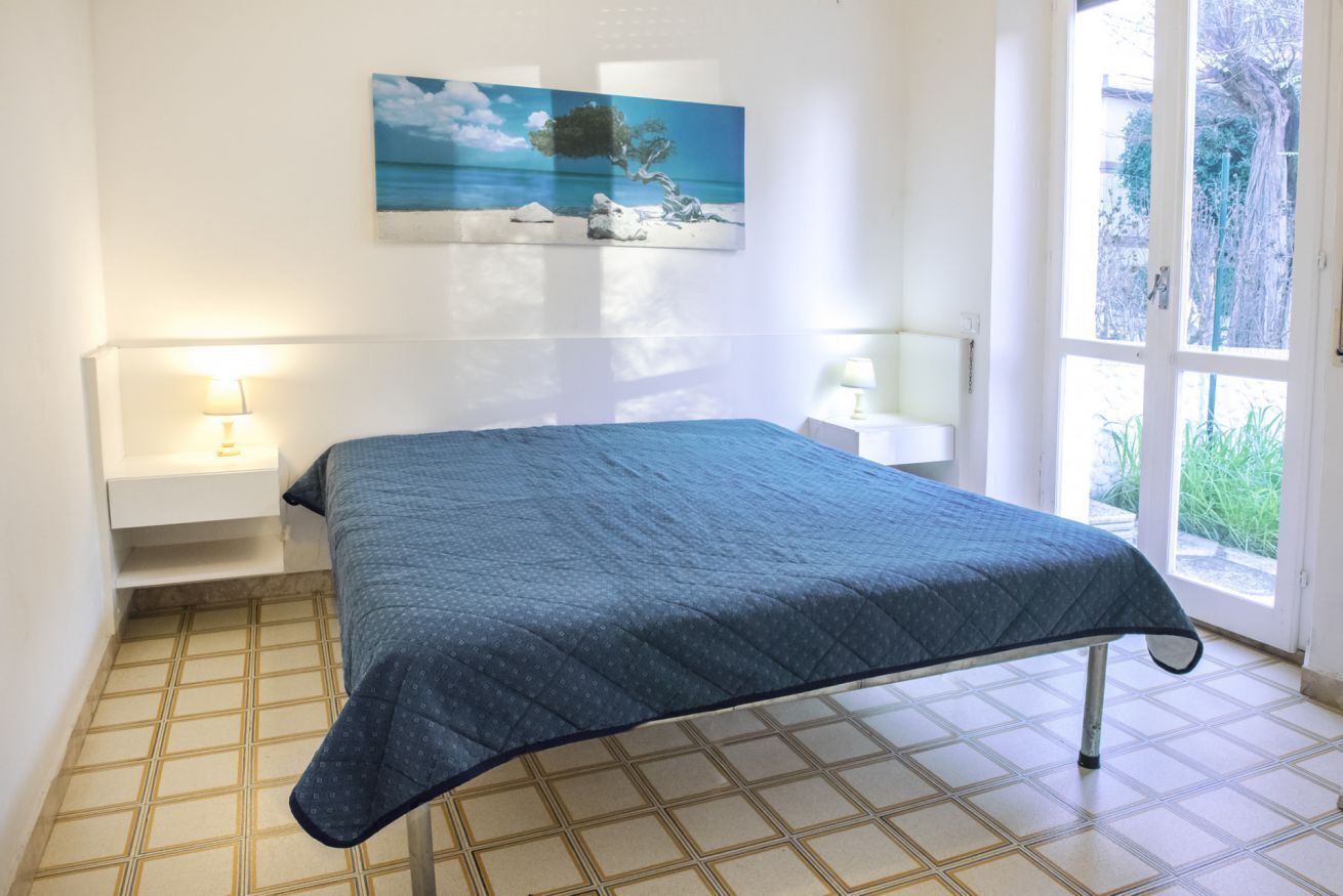 Una camera da letto con un letto, comodini, un quadro e vista dalla finestra.