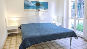 Una camera da letto con un letto, comodini, un quadro e vista dalla finestra.