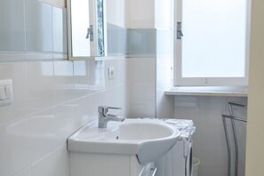 A modern bathroom with a white sink, chrome faucet, and a window above the sink. - M107 - Marcelli, three-room apartment with garden 200m from the sea (Marcelli)