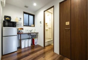 Compact kitchen with microwave, refrigerator, sink, and window.