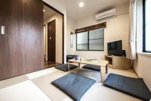 Relax and unwind in this spacious living area, featuring a central table, large window, flat-screen TV, and cozy seating nook.