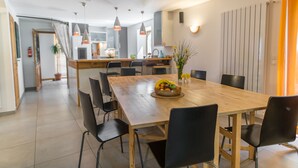 Uma sala de jantar moderna com mesa de madeira, cadeiras pretas e uma fruteira.