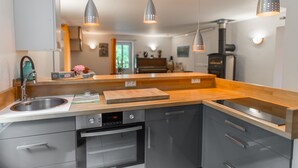 Cozinha moderna com eletrodomésticos de aço inoxidável, bancadas de madeira e iluminação pendente.