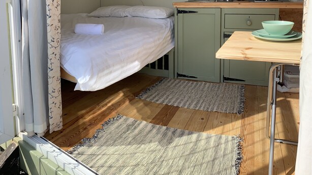 A compact room with a bed, a small kitchenette, and a window. - Hillcrest Hut (Kilgetty)