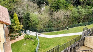 A residential area with a house, a paved pathway, and a fenced garden. - MODERN APARTMENT IN PECHÓN (Pechón)