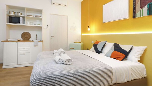 A modern bedroom with a bed, bedside table, and a wardrobe. There is a kitchen area with a microwave and a toaster. - Brand New Guest room in the City Center★Free Wifi (Trieste)