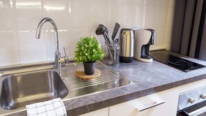 A modern kitchen with a stainless steel sink, a coffee maker, and a small potted plant on the countertop. - Romantic Studio in the heart of Trieste ★Free Wifi (Trieste)