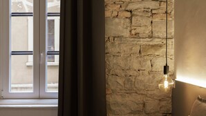 A room with a stone wall, a window with curtains, and a hanging light fixture. - Romantic Studio in the heart of Trieste ★Free Wifi (Trieste)
