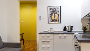 Una cocina moderna con armarios blancos, encimera negra y una cafetera.