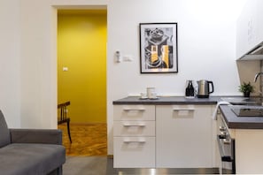 A modern kitchen with white cabinets, a black countertop, and a coffee maker.