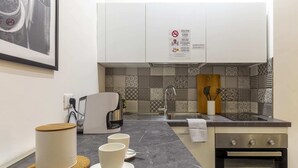 Una cocina moderna con armarios blancos, salpicadero con diseño, una cafetera y un horno empotrado.